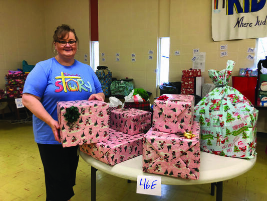 Stephanie Chancellor stands in front of packages that were ready to be distributed to local families through the Adopt a Child program.